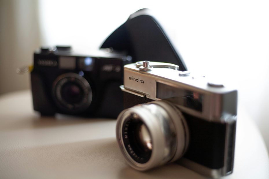 BLACK AND SILVER CAMERA ON BROWN WOODEN TABLE