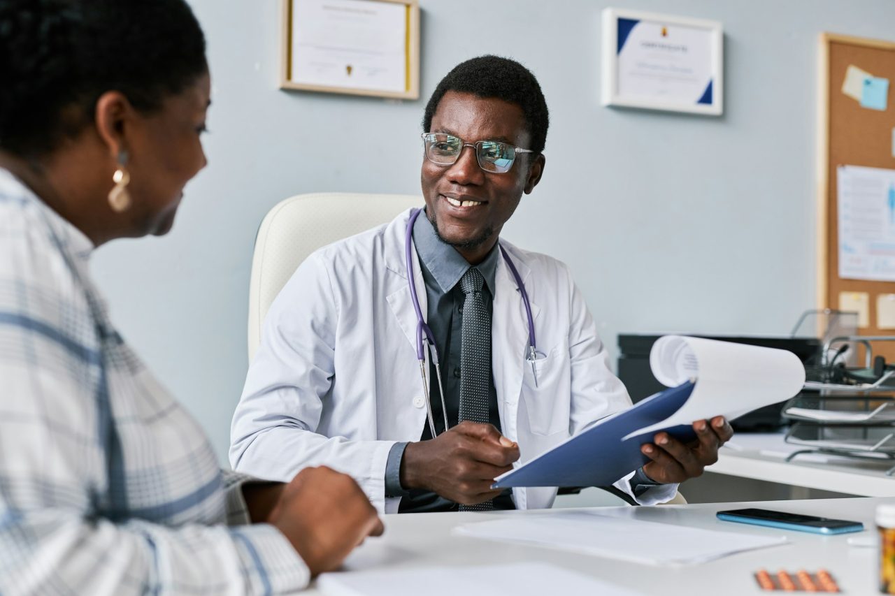 2025 - Início - Home smiling black doctor consulting female doctor in clinic Experienced and Compassionate Team