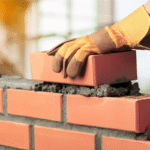 Pedreiro profissional trabalhando em obra com equipamentos de segurança