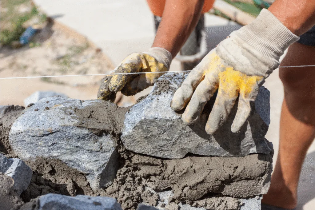 Todo dia, milhares de profissionais da construção civil arriscam suas mãos em canteiros de obras. Entre poeira, cimento, ferragens cortantes e superfícies abrasivas, um único descuido pode resultar em cortes profundos, queimaduras químicas ou lesões permanentes. E você sabe qual é o equipamento mais simples, acessível e eficaz que pode evitar tudo isso? A luva de pedreiro. Pedreiro Fazendo Muro De Pedra